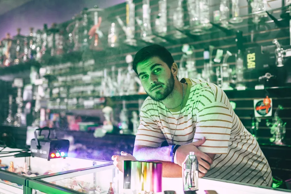 Inside a Get Weird store — a staff member behind glass display cases full of pipes